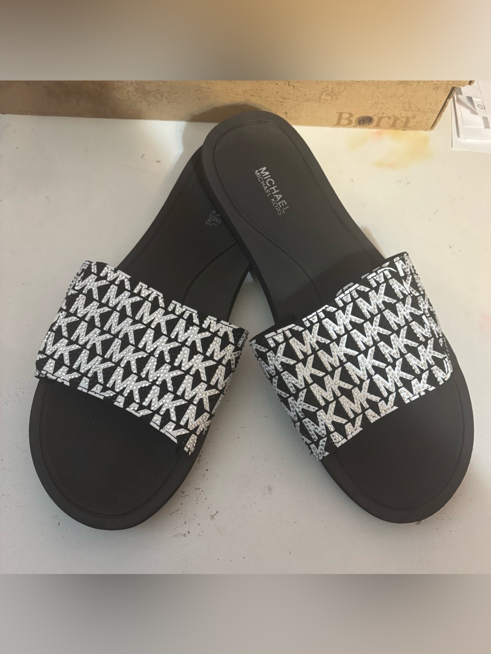Michael Kors black & white slides featuring a signature logo print on the strap.